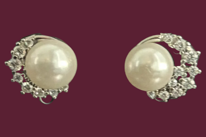 Pair of pearl earrings with silver accents on a black background